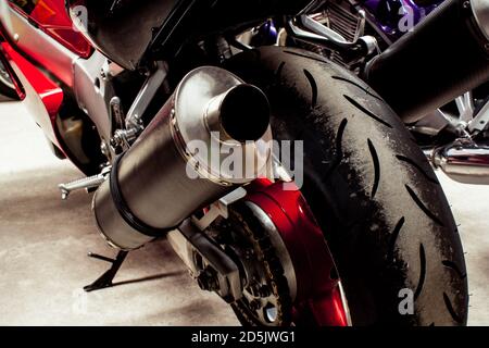 L'arrière du vélo de sport en gros plan dans le garage. Roue, disque de frein, tuyau d'échappement, transmission, amortisseurs. Photo couleur des parties chromées du roa Banque D'Images