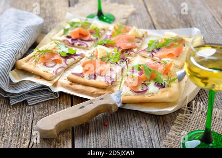 Tarte Flambee d'Alsace avec saumon fumé et feuilles de roquette Servi avec du vin blanc alsacien local Banque D'Images