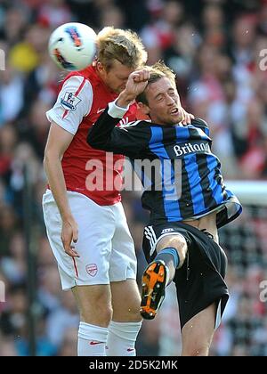 Peter Crouch (à droite) et Arsenal's Per Mertesacker (à gauche) luttez pour le ballon dans les airs Banque D'Images