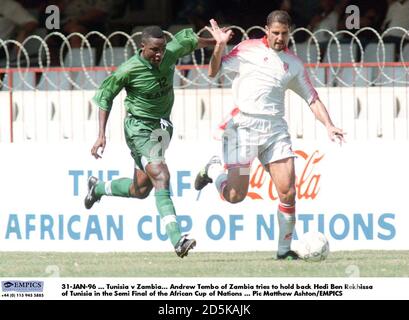 31-JAN-96 ... Tunisie contre Zambie. Andrew Tembo, de Zambie, tente de retenir Hedi Ben Rekhissa, de Tunisie, dans la demi-finale de la coupe africaine des nations Banque D'Images