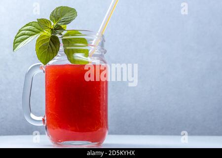 Smoothie au melon d'eau dans un pot avec des feuilles de menthe et un paille cocktail Banque D'Images