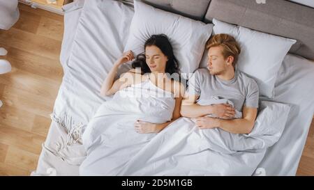 Un jeune couple mignon dormant dans le lit. Tôt le matin, le soleil brille à travers la fenêtre. Banque D'Images