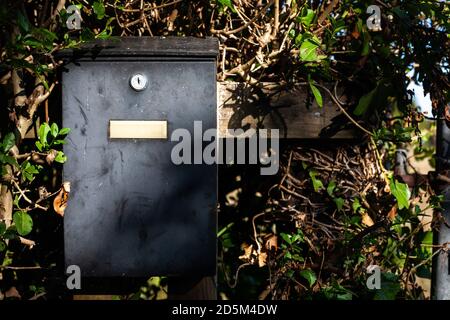 Une boîte postale en métal noir sur une clôture au coucher du soleil dans la campagne anglaise. Livraison par correspondance par courrier postal. Banque D'Images