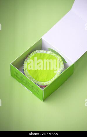 Tampons de nettoyage en coton réutilisables sans déchets organiques pour l'élimination du maquillage en vert et blanc dans la boîte de papier verte sur un fond vert pastel Banque D'Images