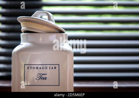 Théière en céramique avec couvercle légèrement entrouvert dans la cuisine. Fenêtre et stores fermés en arrière-plan. Banque D'Images