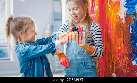 Deux petites Sœurs amusantes jouent et Fool autour avec leurs mains trempées dans la peinture colorée. Ils sont heureux et rient. Objectifs de l'entreprise. Redécoration à Banque D'Images