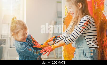 Deux petites Sœurs amusantes jouent et Fool autour avec leurs mains trempées dans la peinture colorée. Ils sont heureux et rient. Objectifs de l'entreprise. Redécoration à Banque D'Images