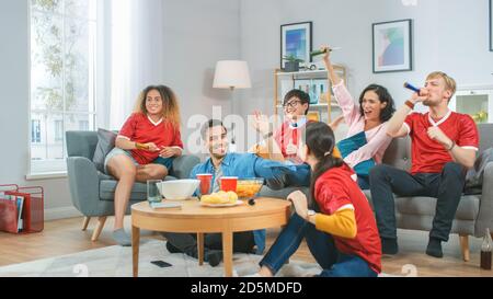 À la maison divers fans de sports de groupe portant le match de match de sport uniforme de l'équipe de montre sur la télévision, ils encouragent l'équipe, célèbrent la victoire après l'équipe Banque D'Images