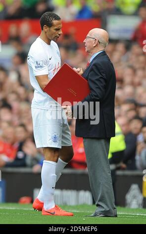 Rio Ferdinand des Queens Park Rangers reçoit un cadeau de Sir Bobby Charlton avant le match contre Manchester United. Banque D'Images