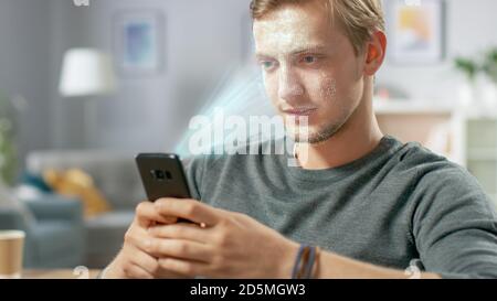 Jeune homme identifié par la reconnaissance faciale biométrique processus de lecture à partir de son smartphone. Concept futuriste : le projecteur identifie l'individu par Banque D'Images