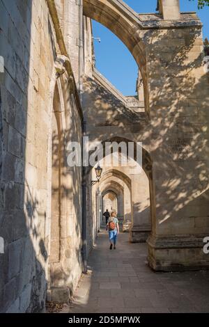 Femme sac à dos, vue arrière d'une femme d'âge moyen portant un sac à dos marchant seul sous les contreforts de la cathédrale de Winchester, Hampshire, Angleterre, Royaume-Uni Banque D'Images