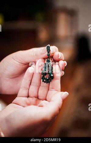 boucles d'oreilles avec pierres vertes dans les mains d'une fille Banque D'Images