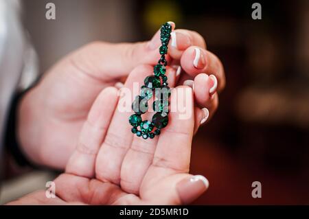 boucles d'oreilles avec pierres vertes dans les mains d'une fille Banque D'Images