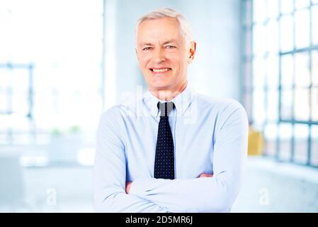 Portrait d'un homme d'affaires souriant portant une chemise et une cravate debout avec les bras croisés dans le bureau. Banque D'Images