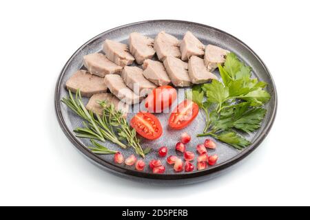 La langue de porc bouillie avec des tomates et des herbes isolées sur fond blanc. Vue latérale, gros plan. Banque D'Images