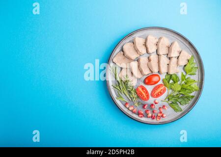 La langue de porc bouillie avec des tomates et des herbes sur fond bleu. Vue de dessus, espace de copie, plan de travail. Banque D'Images