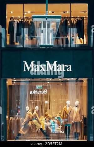 Logo Max Mara et vitrine du magasin la nuit. Quatre mannequins se tenant dans le présentoir à vitrine du magasin. Vêtements tendance dans la boutique. Bergame, Italie - Banque D'Images