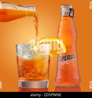 Bouteille et verre de cocktail aperol Spritz avec tranche d'orange. Le barman verse aperol spritz en verre rempli de glaçons. Liqueur sur orange Banque D'Images