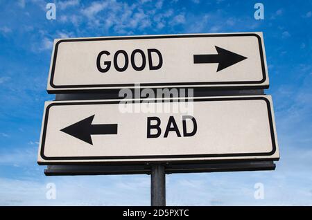 Bon ou mauvais. Deux panneaux de signalisation blancs avec flèche sur poteau métallique avec mot. Route directionnelle. Panneau Crossroads Road, deux flèches. Fond bleu ciel. Deux wa Banque D'Images