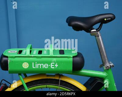 Gros plan et détail d'un vélo électrique Lime vu sur fond bleu. Banque D'Images