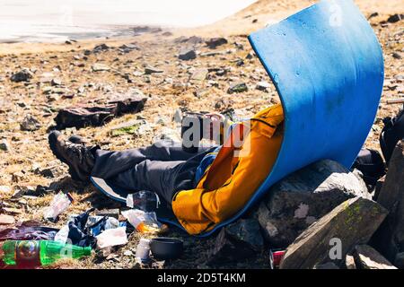 Homme voyageur boit un verre d'une tasse en profitant de la vue magnifique sur le lac alpin assis près de l'équipement de camping. Voyage extérieur aventure style de vie suc Banque D'Images