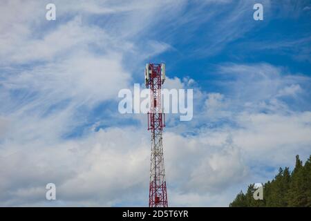 Une tour de cellules en métal rouge-blanc dans un inaccessible Place dans les montagnes de l'Altai sur fond de vert arbres de conifères pour la transmission Banque D'Images