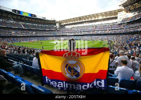 Un fan du Real Madrid porte un drapeau dans les stands alors que les équipes se réchauffent avant le match Banque D'Images