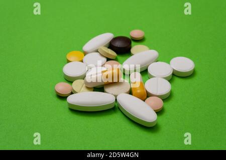 Comprimés ronds colorés et capsules sur fond vert gros plan, macroshot comprimés, isolés. Médicaments en cas de pandémie. Médicaments traitement des maladies. Vitamines Banque D'Images