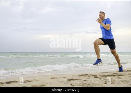 un coureur d'âge moyen part sur une plage de sable de la mer Banque D'Images