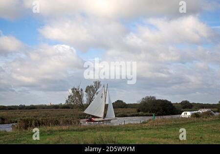 Un yacht-cabine qui se dépare contre le vent sur la rivière Bure sur les Norfolk Broads près de Horning, Norfolk, Angleterre, Royaume-Uni. Banque D'Images