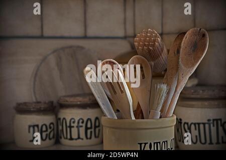 Ustensiles de cuisine et pots de rangement en bois rétro et bien utilisés dans la cuisine, à la lumière du jour Banque D'Images