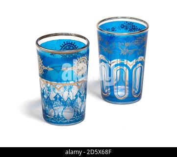 Une paire de verres à thé bleus à bord d'or de style marocain photographiés sur fond blanc Banque D'Images