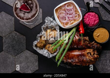 porte-jarret de porc aux pommes de terre, chou sur fond noir Banque D'Images