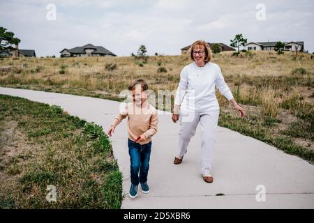 Grand-mère pourchassant petit-fils souriant dehors lors d'une journée nuageux Banque D'Images