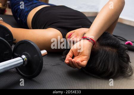 Fatigué après l'exercice et l'entraînement. Femme épuisée, posée sur le sol, respire et se reposant à la maison. Femme en gros plan fatiguée. Trop d'activité. Banque D'Images