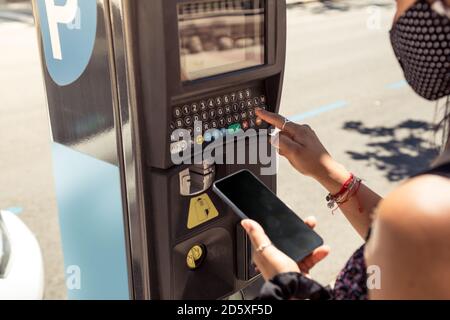 Gros plan de la femme utilisant un appareil de mesure de stationnement avec le smartphone. Banque D'Images