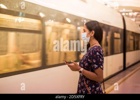 Une jeune femme attend le métro avec un masque médical. Banque D'Images