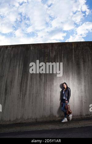 Les jeunes d'Asie femme penchée au mur de béton violoniste Banque D'Images