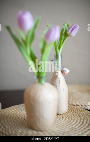 Bouteilles en verre wrappes de papier d'emballage utilisés comme vases à fleurs Banque D'Images