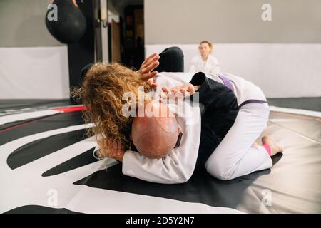 deux judo femmes et hommes combattants arts martiaux pratiquant nouveau techniques sur un tapis de gym Banque D'Images