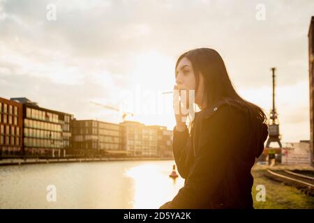 Allemagne, Munster, jeune femme cigarette dans l'avant du port de la ville Banque D'Images