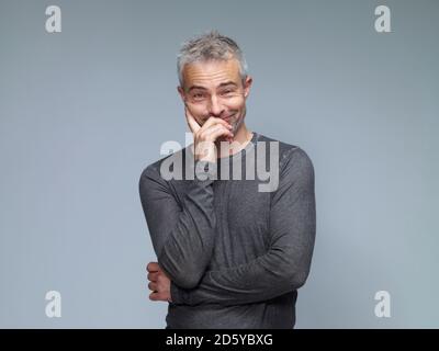 Portrait of smiling mature man, à lever les sourcils devant un arrière-plan vert Banque D'Images