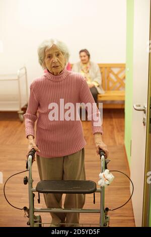 Démence d'âge senior woman with wheeled walker dans une maison de soins infirmiers Banque D'Images