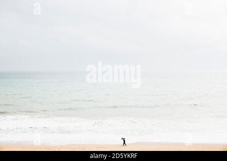 Espagne, Majorque, une personne avec parapluie marchant le long de la plage Banque D'Images