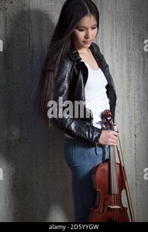 Les jeunes d'Asie femme penchée au mur de béton violoniste Banque D'Images