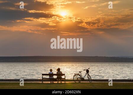 L'Autriche, Burgenland, Illmitz, le lac de Neusiedl, les gens assis sur un banc au coucher du soleil Banque D'Images