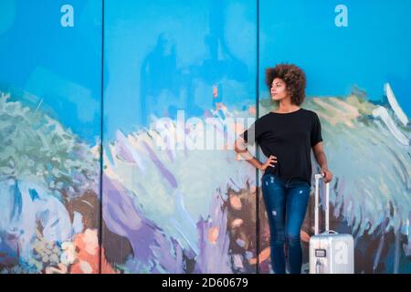 Espagne, Ténérife, jeune femme avec valise à roulettes attendant devant le mur peint Banque D'Images