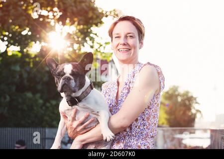 Portrait of smiling woman holding Bouledogue Français Banque D'Images