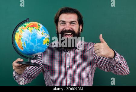 joyeux homme barbu en chemise à carreaux regardant le monde géographique, l'éducation scolaire de géographie. Banque D'Images