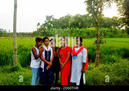 Gros plan de six adolescentes indiennes portant une robe traditionnelle indienne colorée et posant devant un champ de paddy, avec une attention sélective Banque D'Images
